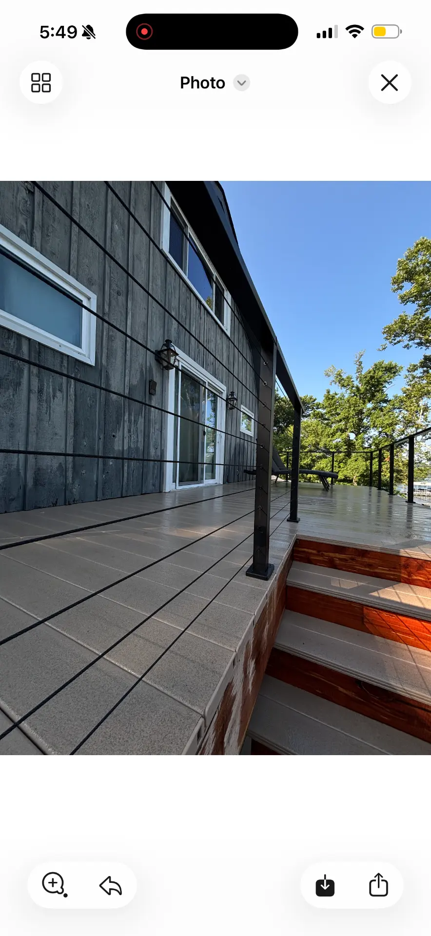Custom deck with tile surface, hardwood stair treads and black cable railing overlooking the lake